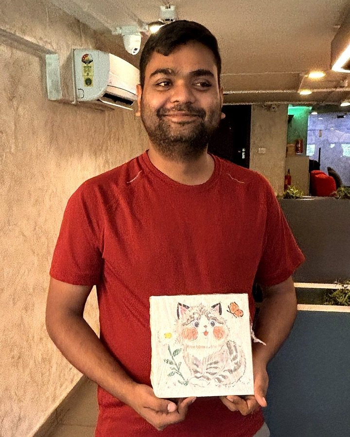 Guest holding a hand-painted ceramic cat tile.
